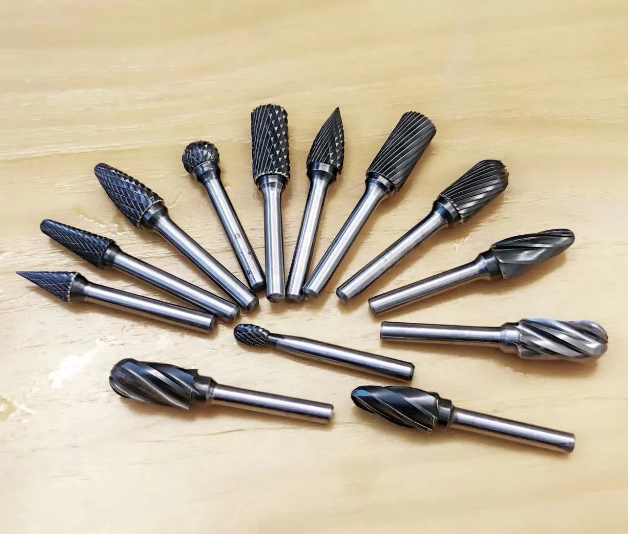 Carbide burr assortment photographed on a workbench, showing different head profiles and flute patterns